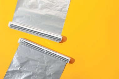 Turuncu arka planda alüminyum folyo ruloları, düz. Metin için boşluk