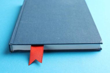 Açık mavi arkaplanda kırmızı kurdele yer imi olan kitap, yakın plan