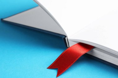 Açık mavi arkaplanda kırmızı kurdele yer imi olan kitap, yakın plan