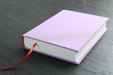 Koyu desenli masa üzerinde kırmızı kurdele yer imi olan kitap, yakın plan.