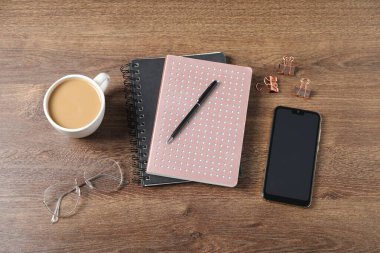 Ofis malzemeleri, bir fincan kahve ve ahşap masa üzerinde akıllı telefon ile düz konum