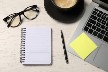 Not defteri, kalem, yapışkan not, bardaklar, kahve ve dizüstü bilgisayar beyaz ahşap masa, düz uzanış