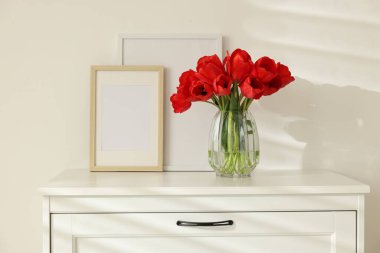 Vazodaki güzel kırmızı laleler ve içerideki dolaptaki çerçeveler.