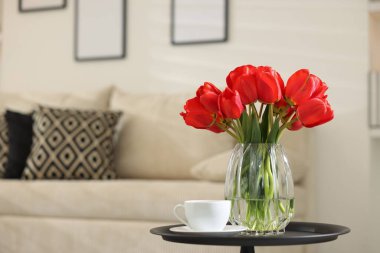 Vazodaki güzel kırmızı laleler ve içerideki masada çay, metin için yer.