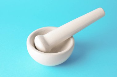 Açık mavi arkaplanda seramik havan ve tokmak, yakın plan