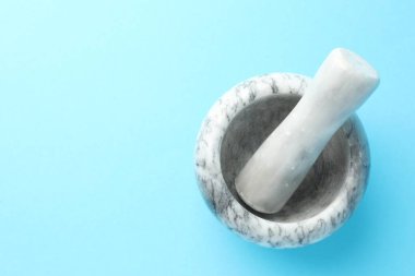 Açık mavi zemin üzerinde mermer harç ve tokmak, üst manzara. Metin için boşluk