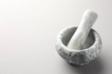 Açık gri arka planda mermer harç ve tokmak, yakın plan. Metin için boşluk