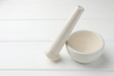 Beyaz ahşap masaya seramik havan topu ve tokmak. Metin için boşluk