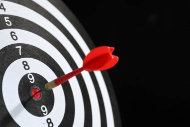 Hedef alınıyor. Siyah arka planda ok olan dart tahtası, yakın plan. Metin için boşluk