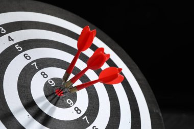 Hedef alınıyor. Siyah arkaplanda okları olan dart tahtası, yakın plan