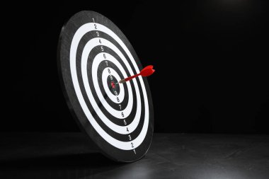 Hedef alınıyor. Siyah arkaplana karşı gri yüzeyde ok olan dart tahtası, metin için boşluk