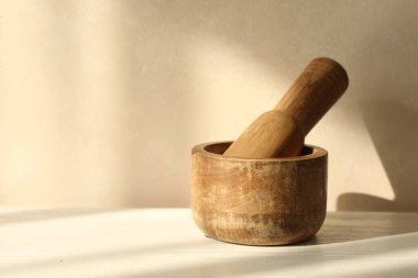 Beyaz masa içerisindeki ahşap havan ve tokmak.