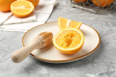 Tahta sıkacağı ve taze portakallar gri masada, yakın plan.