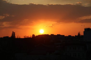 Gün batımında gökyüzünün altında binalar ve ağaçlar