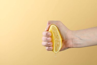 Sarı arka planda limon sıkan kadın, yakın plan. Metin için boşluk