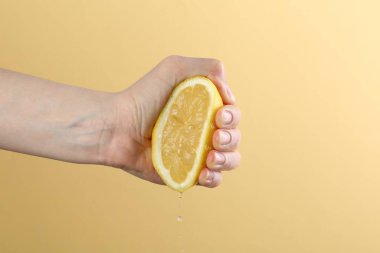 Sarı arka planda limon sıkan kadın, yakın plan.