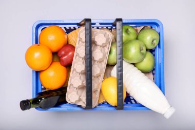 Hafif arka planda ürünlerle dolu plastik alışveriş sepeti, üst görünüm