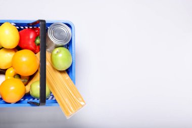 Işık arka planda ürünlerle dolu plastik alışveriş sepeti, üst manzara. Metin için boşluk