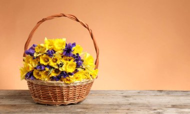 Mercan zeminine karşı ahşap masanın üzerinde güzel çiçekler olan hasır sepet. Metin için boşluk