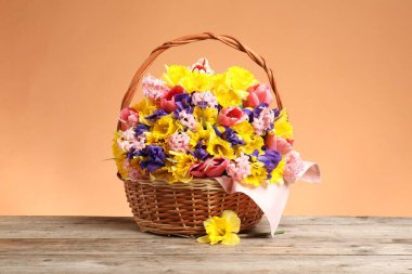 Tahta masada mercan zemin üzerinde güzel çiçeklerle dolu bir sepet.