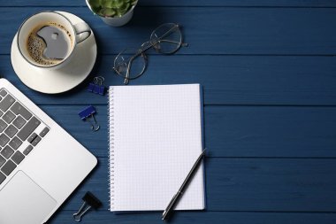Kalemli, dizüstü bilgisayarlı, gözlüklü, ataçlı, mavi ahşap masadaki kahveli, düz yataklı defter. Metin için boşluk