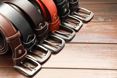 Ahşap masada bir sürü deri kemer, yakın plan. Metin için boşluk