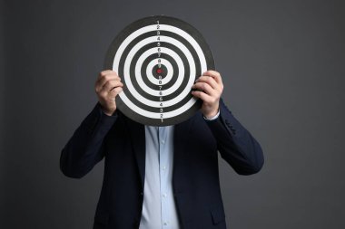 Hedef alınıyor. Gri arka planda dart tahtası olan adam.