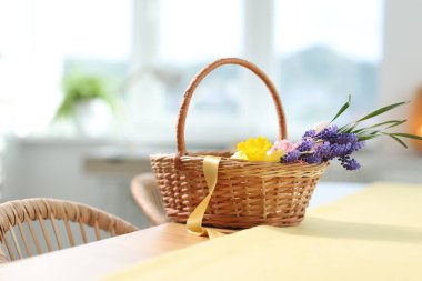 İçerideki masada güzel çiçekler olan hasır sepet.