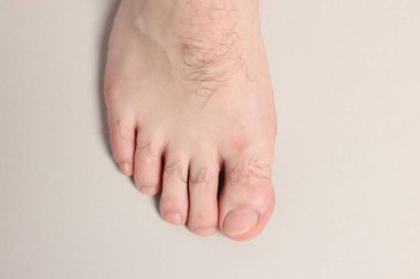 Açık gri arka planda çıplak ayaklı adam, üst görünümde.