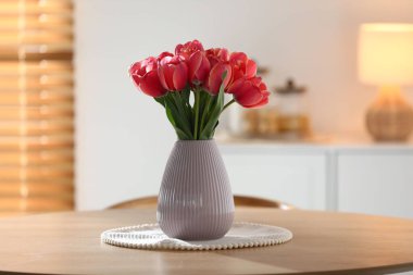 İçerideki ahşap masada vazodaki güzel laleler.