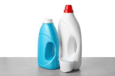 Beyaz arkaplana karşı gri masada yumuşatıcı şişeler