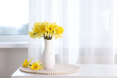 Evdeki beyaz masada vazodaki güzel nergisler. Metin için boşluk