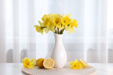 Vazodaki güzel nergisler ve evdeki beyaz masada limonlar.