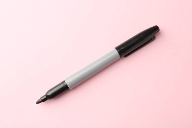 Açık pembe arkaplanda bir siyah işaret, üst görünümde.