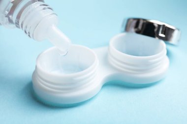 Kontakt lens solüsyonu açık mavi arkaplanda, yakın plan