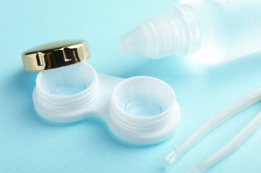 Açık mavi arkaplanda kontak lensler, çözüm ve cımbızlar, yakın plan