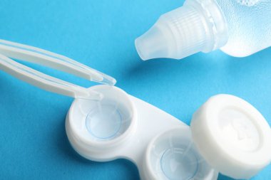 Mavi arkaplanda kontak lensler, çözüm ve cımbızlar, üst görünümde