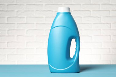 Açık mavi masada beyaz tuğla duvara karşı yumuşatıcı.