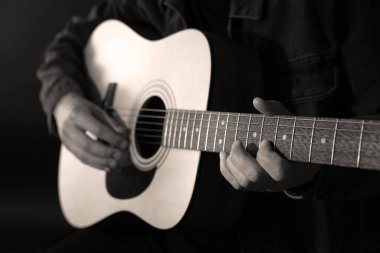Karanlıkta gitar çalan adam, yakın plan. Siyah ve beyaz etkisi