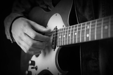 Karanlıkta gitar çalan adam, yakın plan. Siyah ve beyaz etkisi