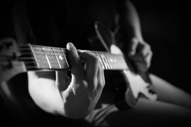 Karanlıkta gitar çalan adam, yakın plan. Siyah ve beyaz etkisi