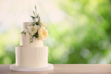 Dışarıdaki ahşap masada çiçeklerle süslenmiş güzel bir düğün pastası. Metin için boşluk