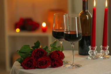 Restorandaki masada kırmızı şarap, yanan mumlar ve güller. Romantik yemek.