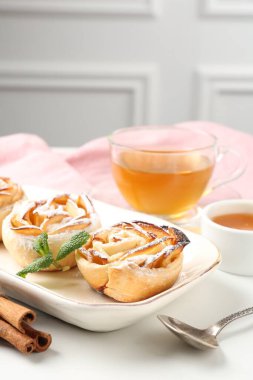 Nane, bal, tarçınlı taze elma gülleri ve beyaz masada çay, yakın plan.