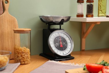 Kitchen scale, products and cooking utensils on wooden table