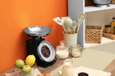 Kitchen scale, products and cooking utensils on wooden table