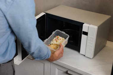 Yemek kabını mikrodalgaya koyan adam, yakın plan.