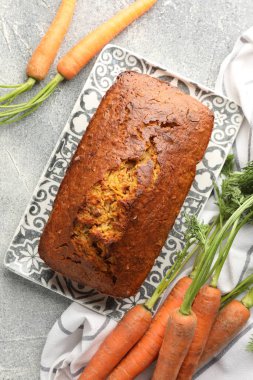 Lezzetli havuçlu kek ve sebzeler gri desenli masada, düz yatıyordu.