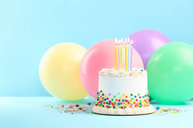 Renkli şekerli nefis bento keki ve açık mavi masada yanan mumlar. Metin için boşluk