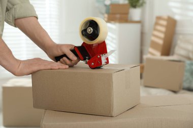 Karton kutuyu bantla kapatan adam içeride, yakın plan.